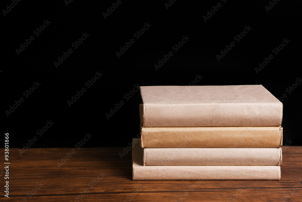 Pile of closed old books on wooden table against black background Pile of closed old books on wooden table against black background