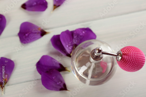 Bottle of perfume and flowers petals on fabric background