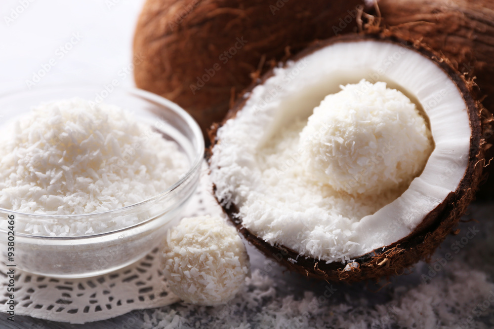 Candies in coconut flakes and fresh coconut on color wooden background Candies in coconut flakes and fresh coconut on color wooden background
