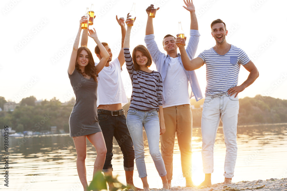 Obraz premium Young people with beer on the riverside