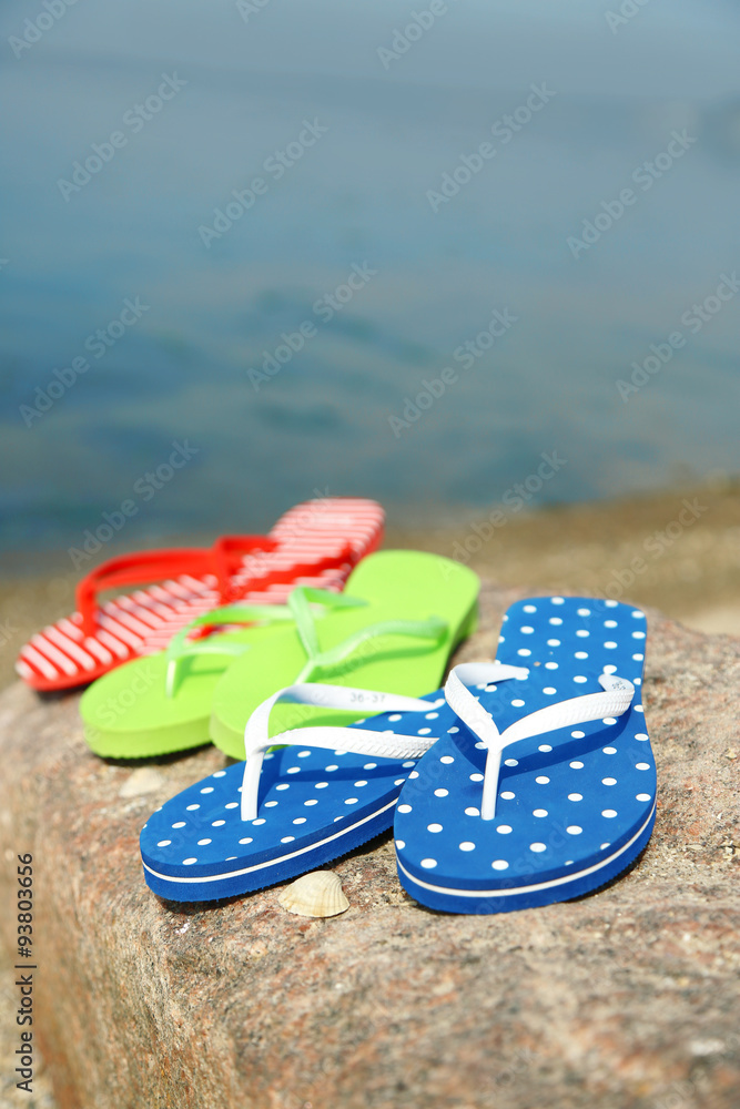 Naklejka premium Bright flip-flops on stone, nature background