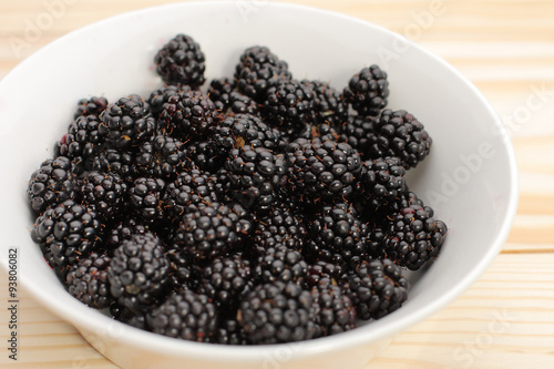 Blackberries  in a white bowl on wooden table