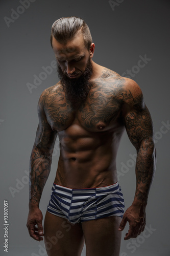 Muscular nude man with tattooed body.