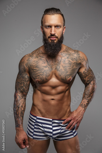 Muscular nude man with tattooed body.