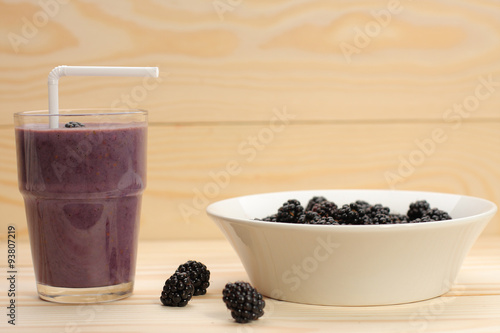 Smoothie from blackberries  in a glass and blackberries  on wood