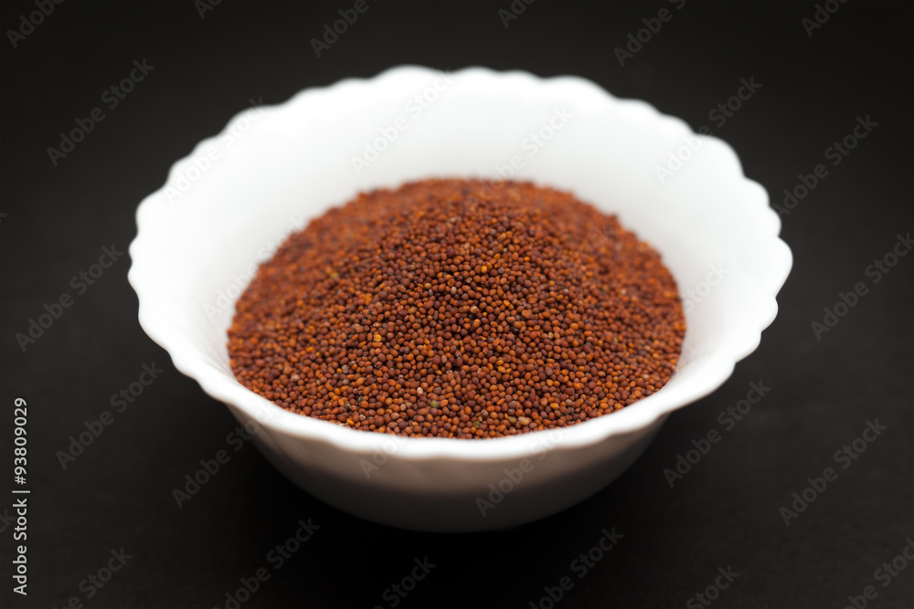 Organic Small Brown Mustard Seeds (Brassica juncea) in white ceramic bowl on dark background. Organic Small Brown Mustard Seeds (Brassica juncea) in white ceramic bowl on dark background.
