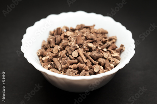 Organic Ganthoda or Long pepper Roots (Piper longum) in white ceramic bowl on dark background.