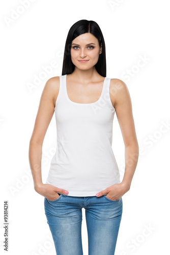A brunette woman in a white tank top and denims. Hands are in the pockets. Isolated. © ImageFlow