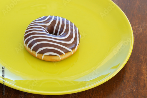 donut with chocolate zebra colors on the color plate and brown background. top view. space for inscriptions.