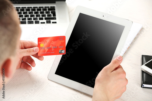 Man holding credit card and tablet on workplace background