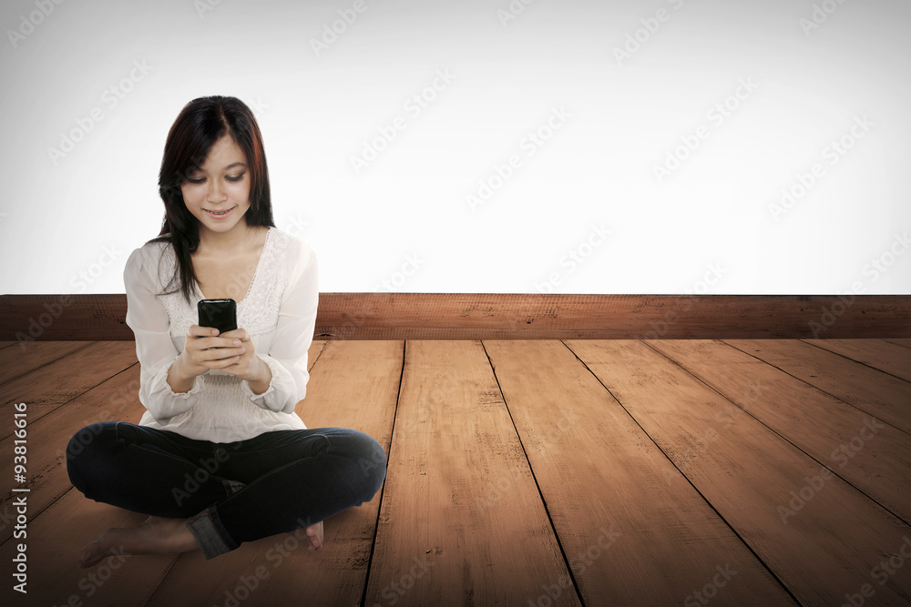 Pretty asian girl using cellphone on the wooden floor Pretty asian girl using cellphone on the wooden floor