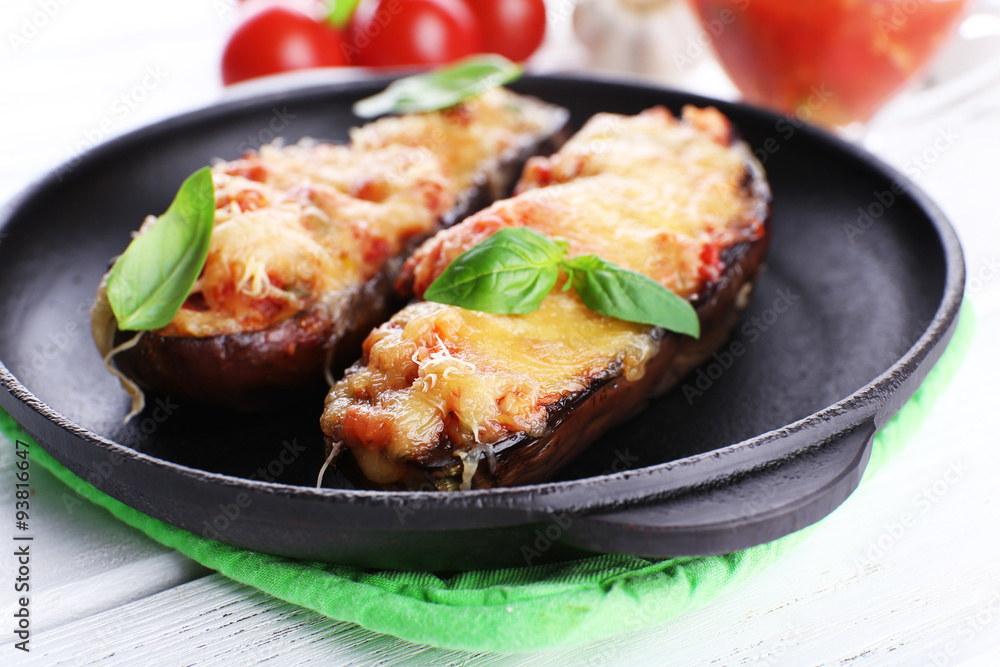 Dish of eggplant with cherry tomatoes and cheese in black pan on wooden table, closeup Dish of eggplant with cherry tomatoes and cheese in black pan on wooden table, closeup