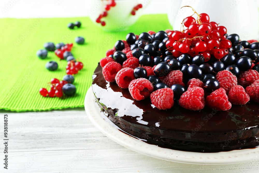 Delicious chocolate cake with summer berries on wooden table with green napkin, closeup Delicious chocolate cake with summer berries on wooden table with green napkin, closeup