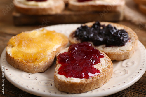 Fresh toast with butter and different jams on table close up