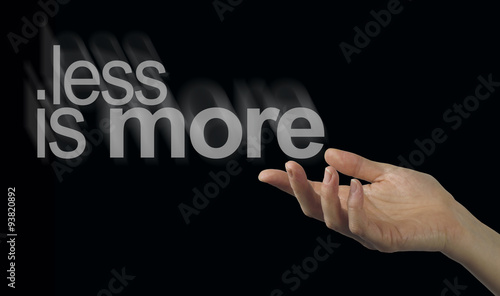 Wallpaper Mural Sharing a less is more philosophy - Female hand appearing to release a phrase LESS IS MORE on a black background Torontodigital.ca