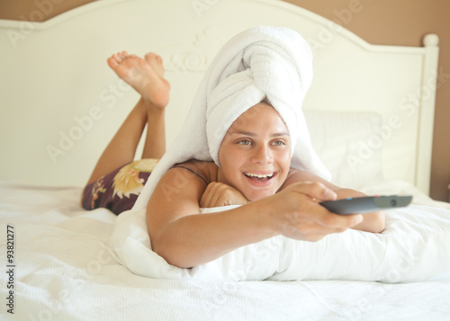 young beautiful woman on the bed with a TV remote control