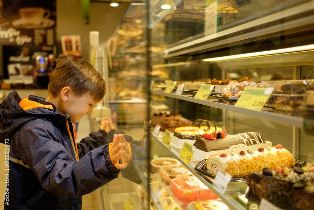 Little boy near display with cakes in a grocery store