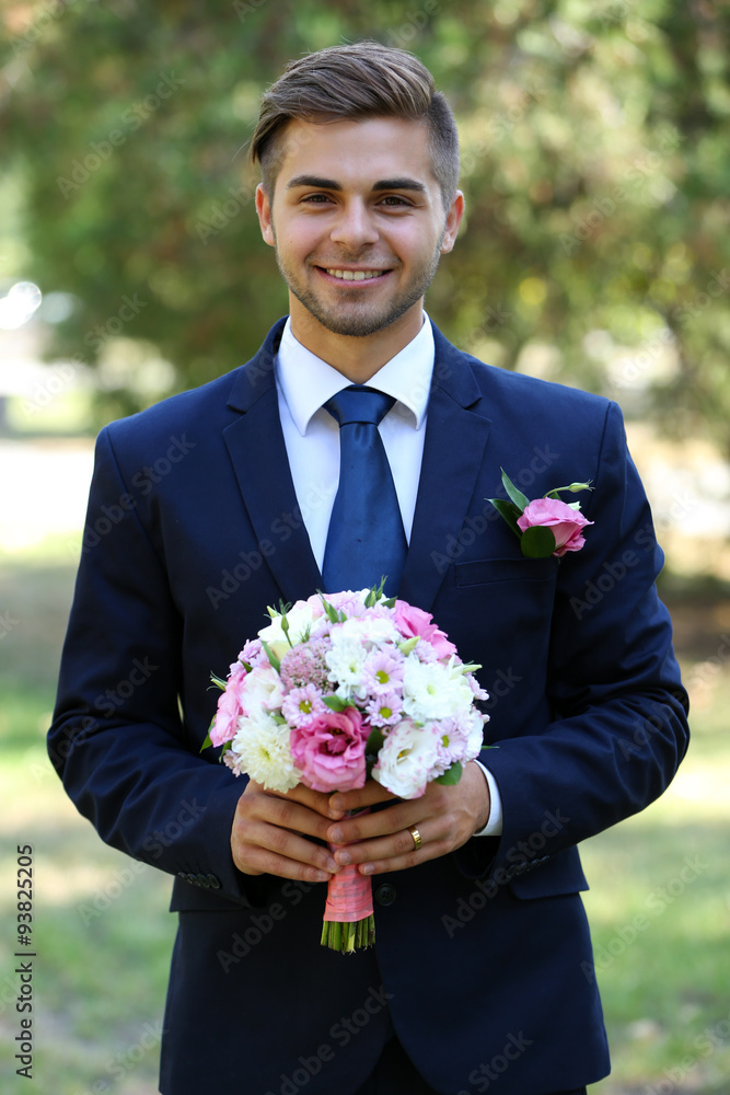 Groom holding wedding bouquet outdoors Groom holding wedding bouquet outdoors