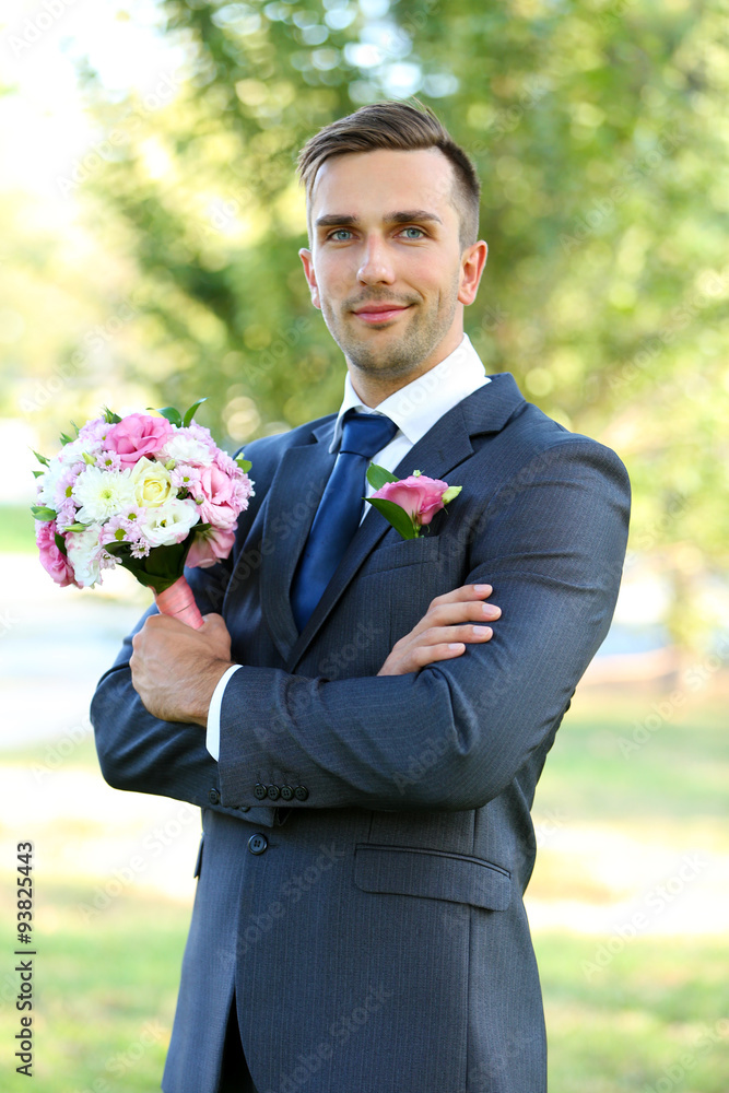 Groom holding wedding bouquet outdoors Groom holding wedding bouquet outdoors