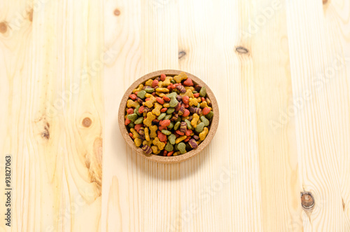 Dry dog food in wooden dish and wooden background