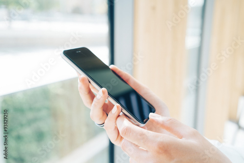 Girl holding smart phone in a hand on the blured background.