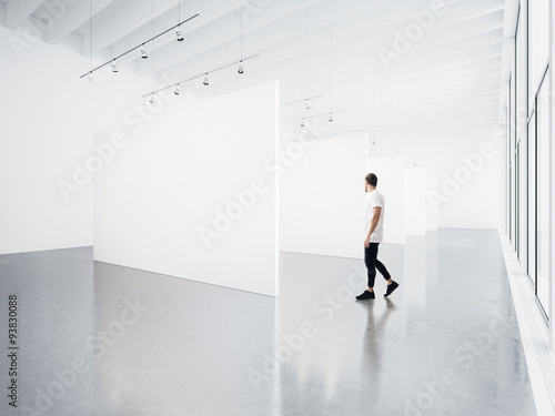 Gallery interior with white canvas and young man. 