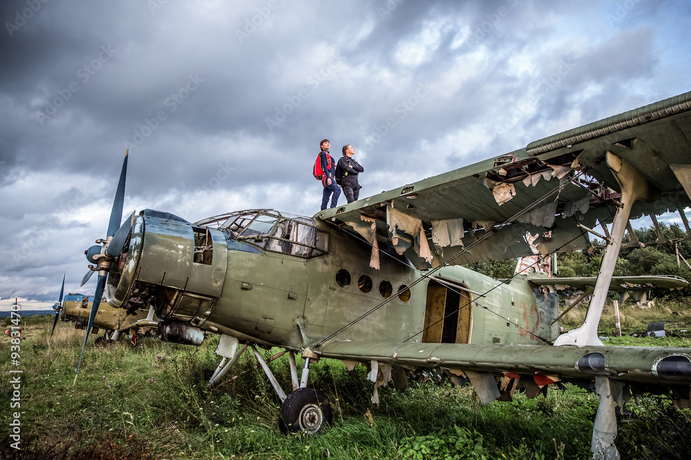 Fototapeta premium Two sportswoman parachutist on the roof of an old airplane on the background of a stormy sky