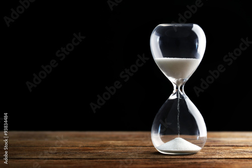 Hourglass on wooden table on grey background photo