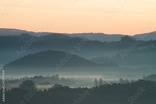 Blue morning. Hills and forests lines in mountain valley during autumn sunset. Natural mountain landscape in cold mist