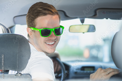 Junger Mann mit Sonnenbrille sitzt im Auto © DDRockstar