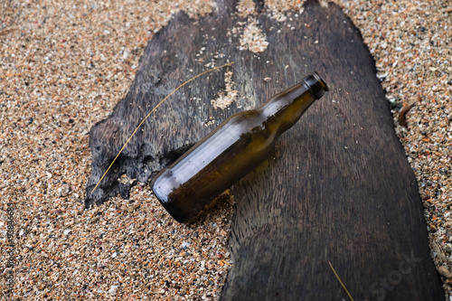 Beer Bottle lay on the Timber at the Sand 