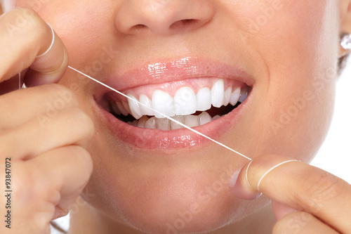 Woman teeth with dental floss.