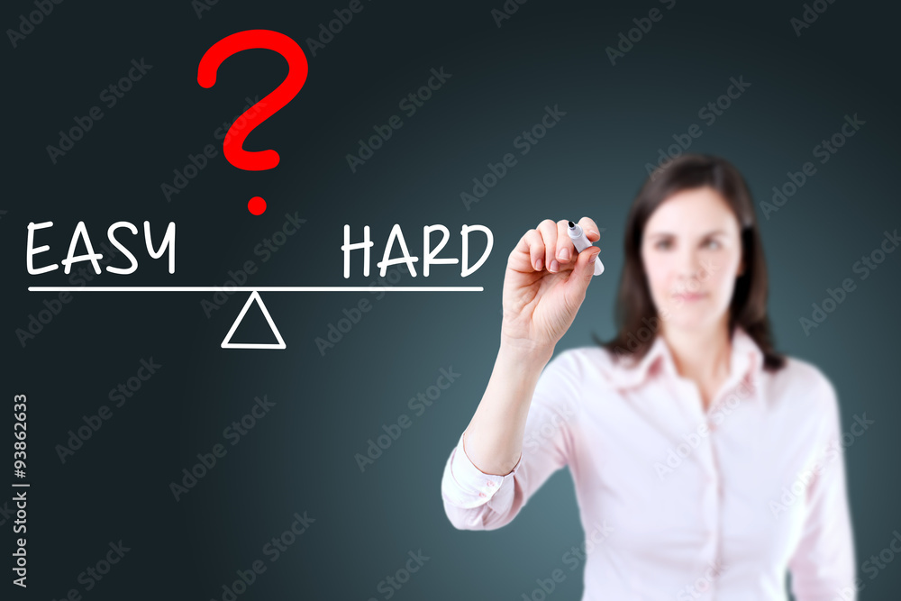 Young business woman writing easy and hard compare on balance bar. Blue background. Young business woman writing easy and hard compare on balance bar. Blue background.