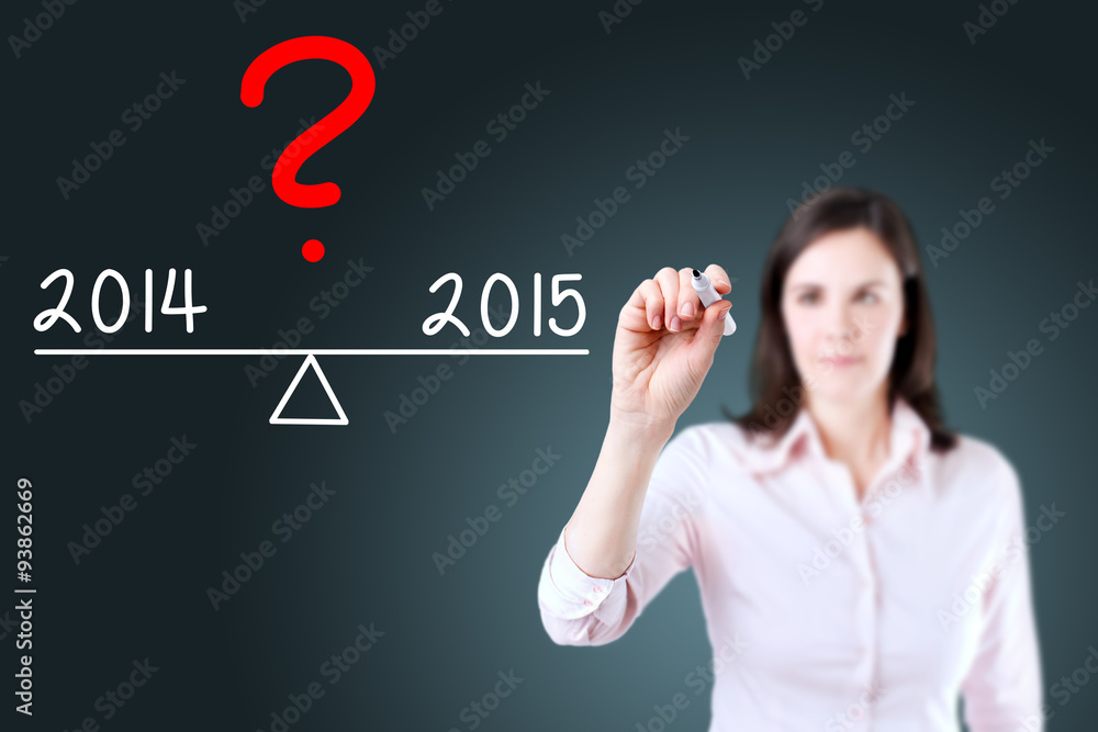 Young business woman writing 2014 and 2015 compare on balance bar. Blue background. Young business woman writing 2014 and 2015 compare on balance bar. Blue background.