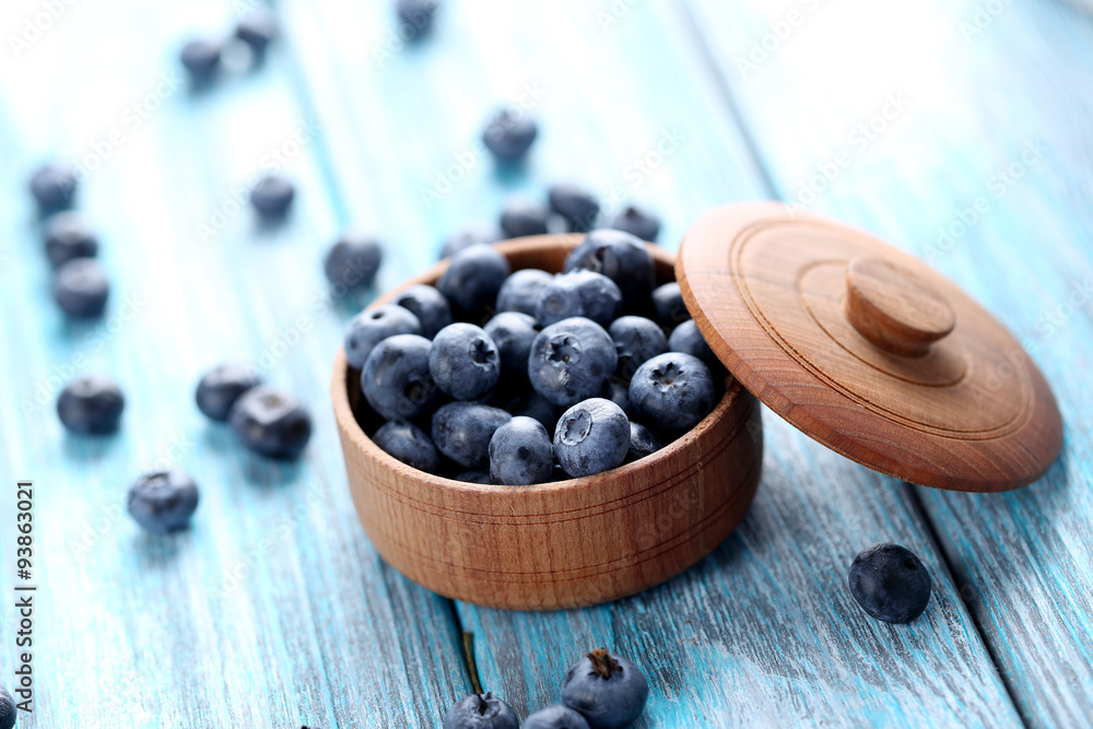 Tasty blueberries in bowl on a blue wooden table Tasty blueberries in bowl on a blue wooden table