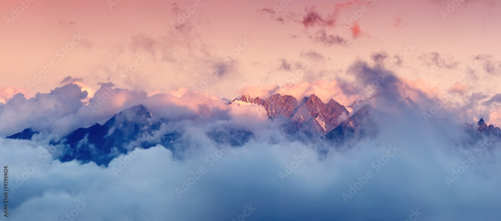 High mountain range in the clouds during sunrise. Beautiful panoramic landscape