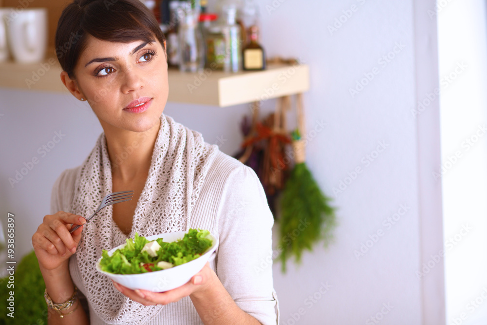 Young woman eating fresh salad in modern kitchen Young woman eating fresh salad in modern kitchen