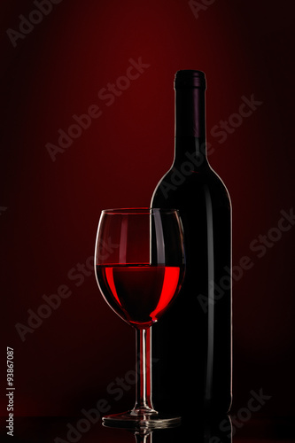 bottle of wine and wine glass on red background