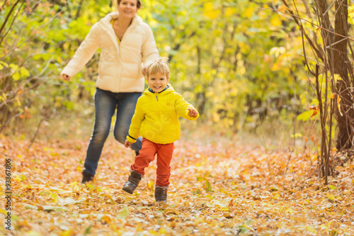 Happy woman and her little son having fun in autumn park