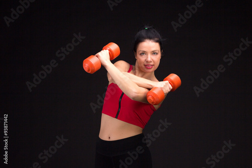 Brutal athletic woman pumping up muscules with dumbbells © PaulShlykov