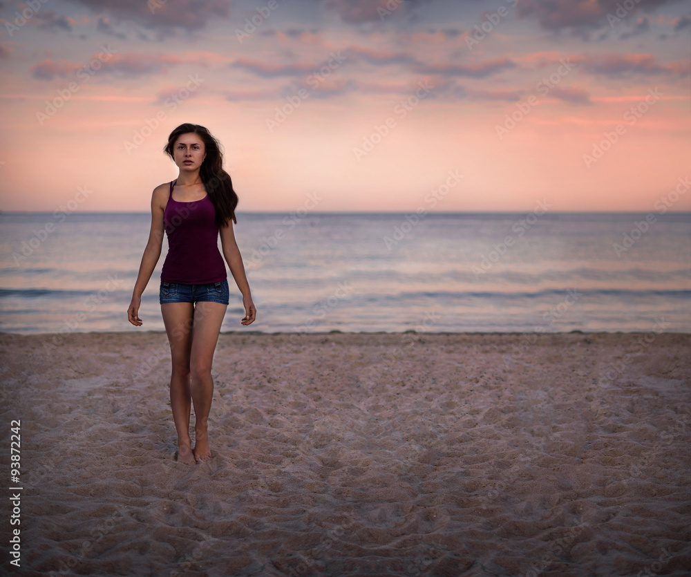 Young woman standing on a beach and enjoying the sun Young woman standing on a beach and enjoying the sun