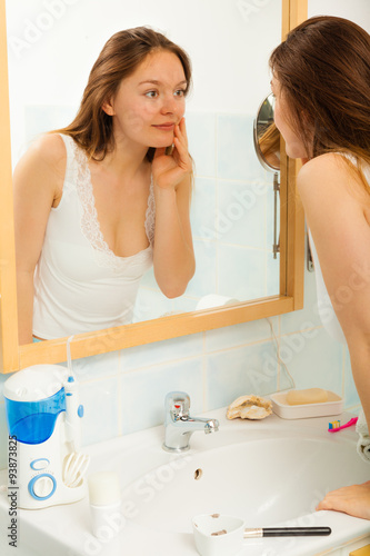 Woman without makeup in bathroom.