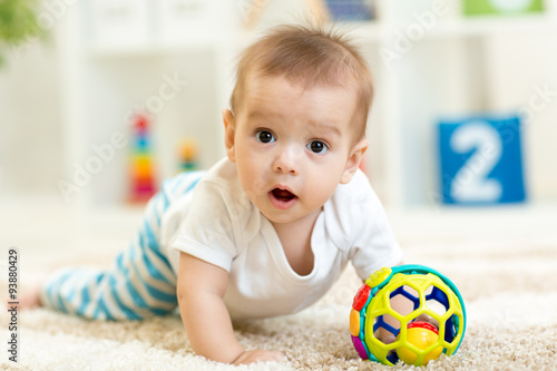 Joyful baby crawling on the floor in nursery room