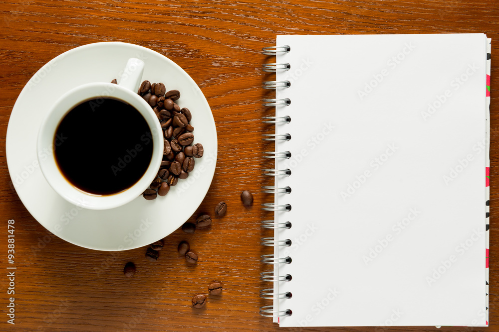 note pad and a cup of coffee with roasted grains note pad and a cup of coffee with roasted grains