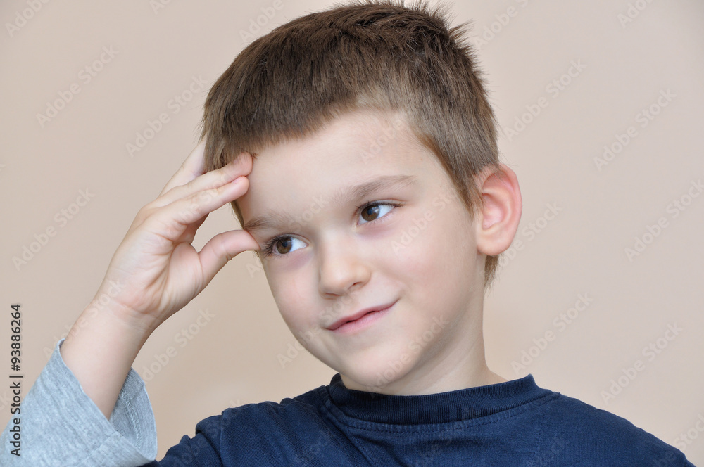 Cute young smiling boy thinking and holding fingers on head Cute young smiling boy thinking and holding fingers on head