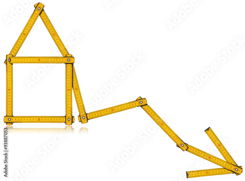 Real Estate - Decreasing Sale Graph / Wooden yellow meter in the shape of house and diagram of decrease. Isolated on white background.