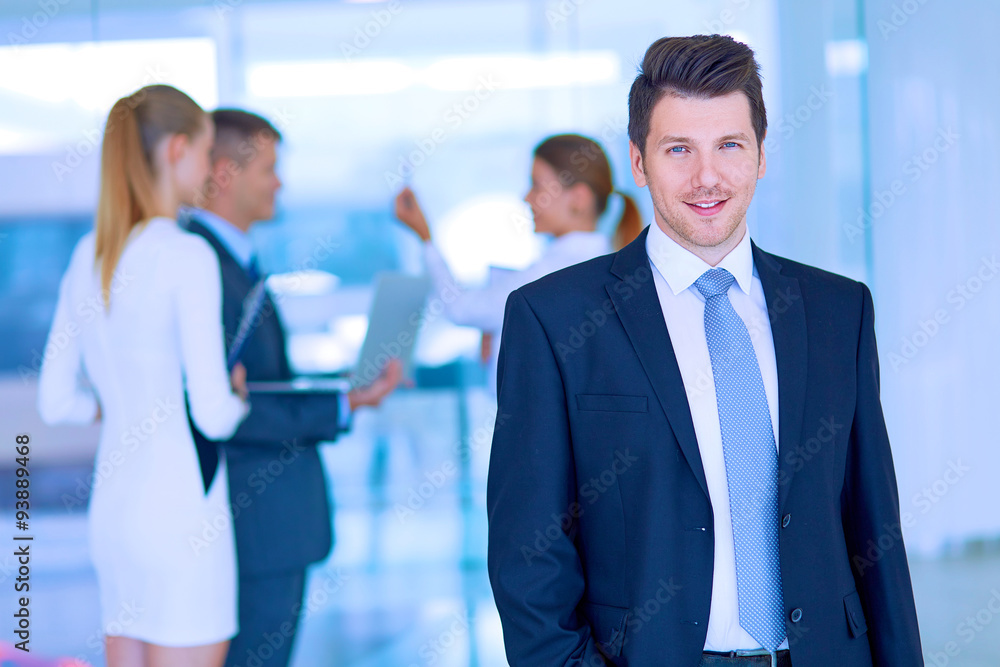 Portrait of young businessman in office with colleagues in the Portrait of young businessman in office with colleagues in the