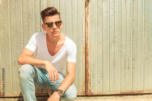 Canvas Print skinny man pose outside sitting with hand on his knee