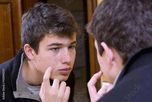 Photos Teenager examining acne in the mirror
