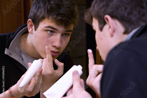 Teen with getting acne cream treatment photo